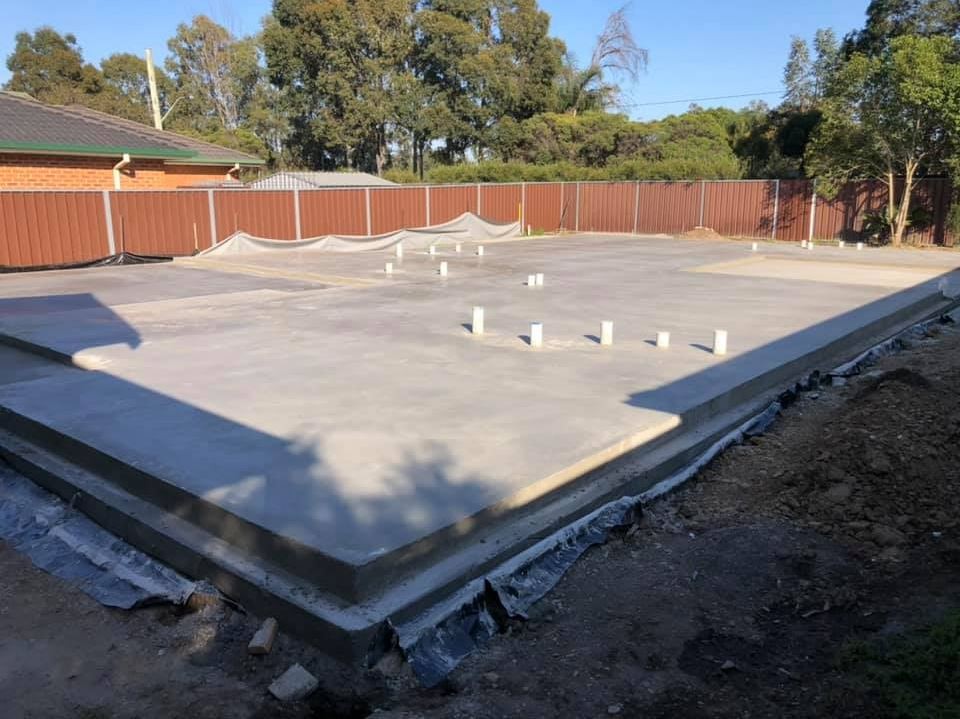 Concrete slab being poured over steel reinforcement mesh
